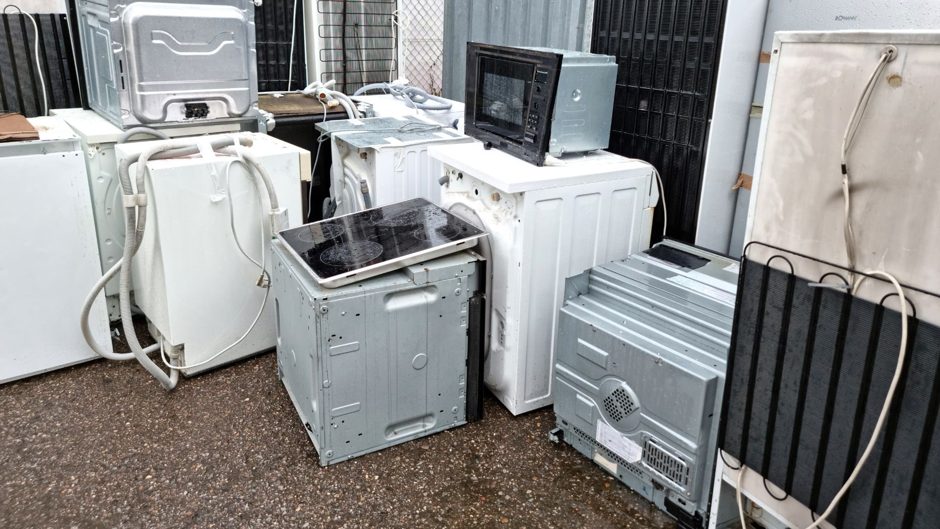 Pile of discarded white household appliances and electronics in storage area