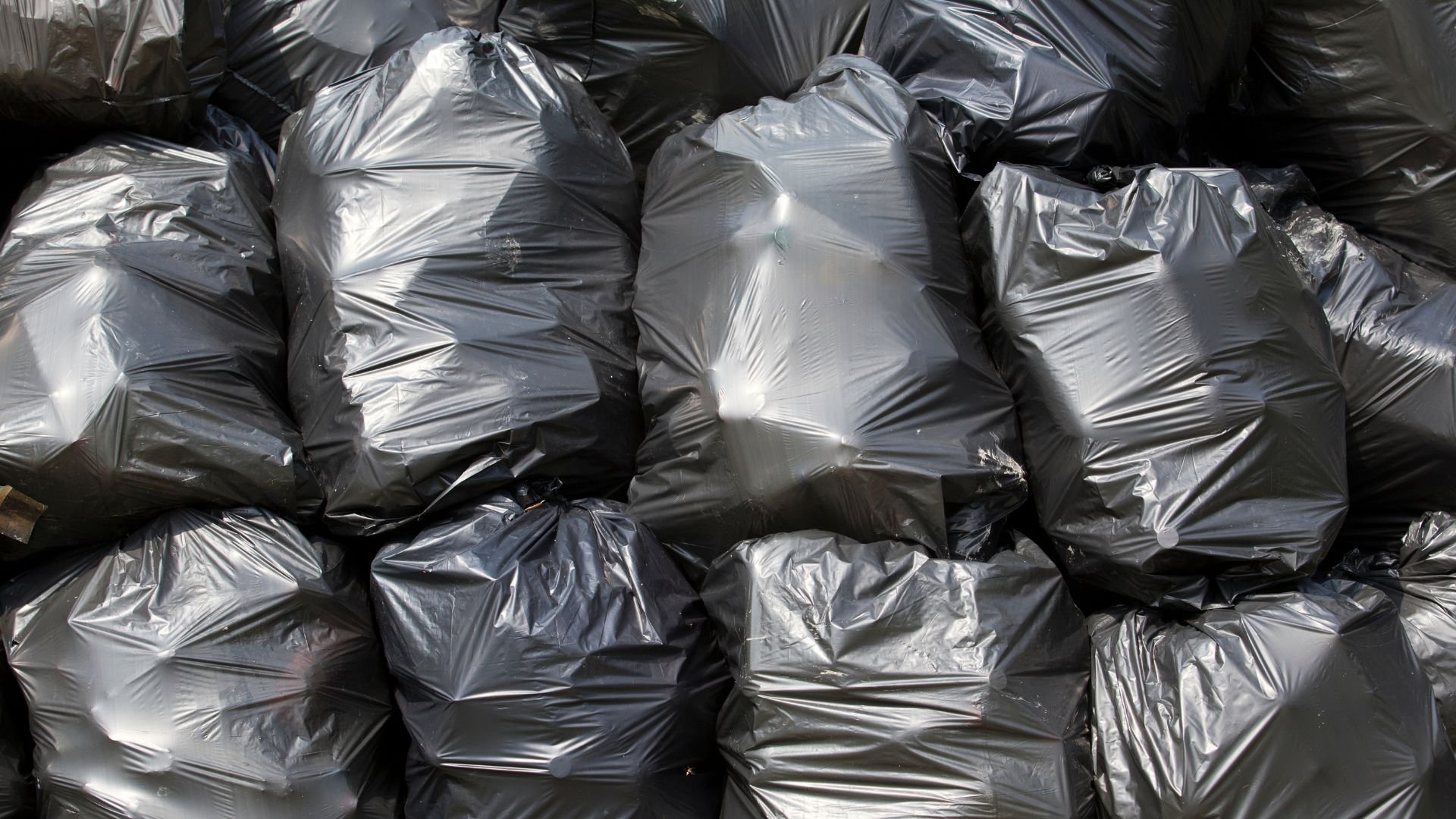 Pile of gray and black plastic trash bags stacked together